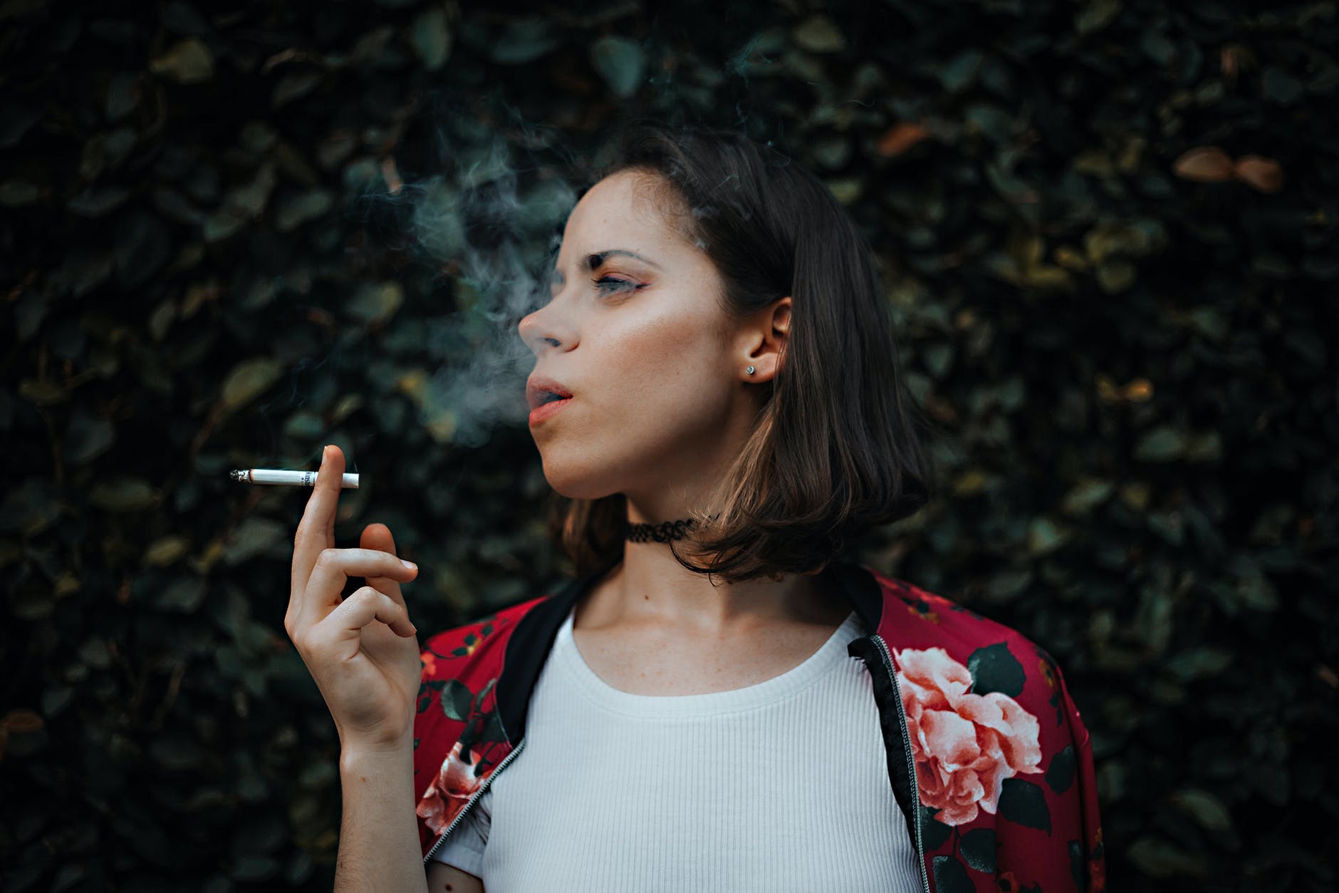 woman in white top and red floral jacket smoking cigarette