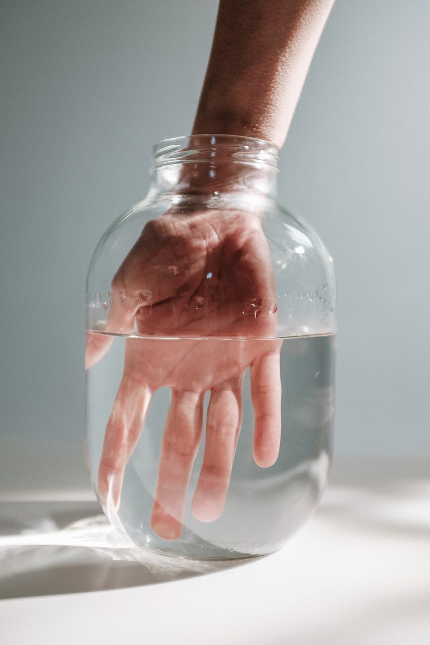 photo of person s hand submerged on a jar with water