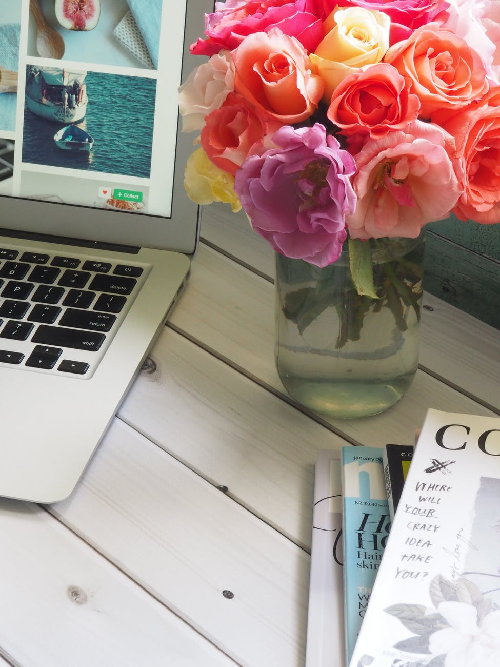 assorted color flower arrangement in clear glass vase beside a laptop
